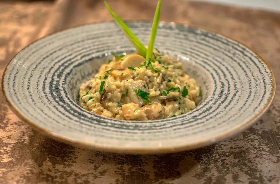 Risotto cremoso de hongos servido en un plato de cerámica